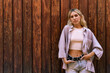 © Juanjo Díaz - Blonde woman looking at camera poses with style leaning against wooden wall.