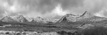 Black And White Majestic Winter Panorama Landscape Image Of Mountain Range And Peaks Viewed From Loch Ba In Scottish Highlands With Dramatic Clouds Overhead