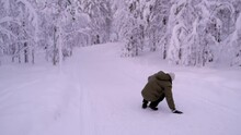 Defocused Mature Man In Hat, Jacket Walking Through Snow Walks Along Road In Park, Forest, Slips On Ice, Falls, Active Lifestyle, Injuries In Winter, Winter Landscape, Slippery Shoes