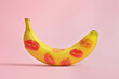 Banana covered with red lipstick marks on light pink background. Potency concept