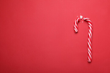 Broken sweet Christmas candy cane on red background, top view. Space for text