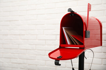 open red letter box with envelopes near white brick wall. space for text