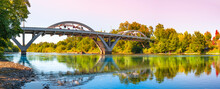 Rogue River Bridge, Spanning Redwood Highway 25 In Grants Pass, Josephine County, Oregon. The Arching Bridge Reflected On Rougue River At Sunset.