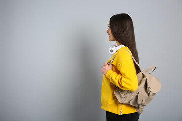 Wall Mural - Beautiful young woman with stylish leather backpack and headphones on grey background. Space for text