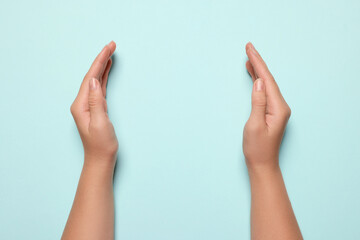 Wall Mural - woman holding on turquoise background, closeup of hands. space for text