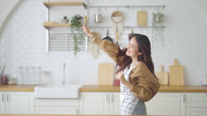 Poster - Asian young woman dancing in kitchen room. She happy and relaxing at free time on weekend