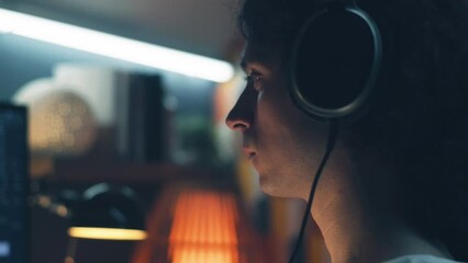Wall Mural - man in headphones browsing the internet and social networks on computer at home at night and listeni