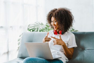 Wall Mural - Young pretty african amerian woman studying online with laptop at living room.