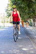 © G-images - Happy old woman in sportswear riding bicycle outdoors on countryside road
