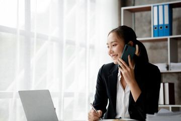 Wall Mural - Beautiful Asian woman executives, business executives, marketing executives are talking on the phone with customers to contact the company for marketing. Marketing management concept.