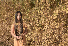Portrait Of Asian Woman In Yellow Dress Near Foliage In Autumn Colors