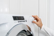 closeup of female hand turn on washing machine indoors
