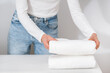woman neatly folding terry towels on table indoors