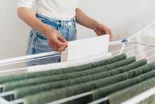woman hanging clean terry towels on drying rack indoors
