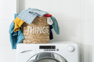 dirty clothes in basket on washing machine indoors