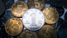 One Chinese Yuan Resting On Several Five Jiao Coins Is Shot Close-up. Many Coins In Denominations Of One Chinese Yuan In The Background. One Yuan Coin Minted In 2017