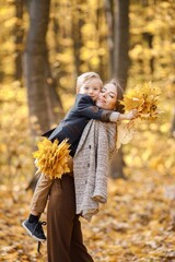 Wall Mural - Mother and her son playing and having fun in autumn forest