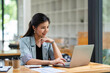 © crizzystudio - Asian businesswoman working with laptop at her desk in the modern office