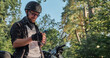 © perfectlab - Young male biker in helmet using mobile phone and smiling sitting on a motorcycle