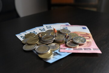 Miniature figurines of worker working on a pile of money