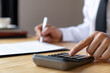 © crizzystudio - Banking and savings finance concept, close-up of businessman's hands pressing a calculator. and fill out the documents for tax refund and tax savings