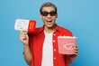 Young excited cheerful cool happy overjoyed fun man of African American ethnicity in 3d glasses watch movie film hold bucket of popcorn in cinema ticket isolated on yellow background studio portrait.