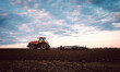 Tractor on field tilling the soil during sunset