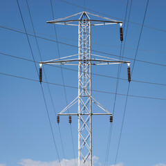 A Single Steel Tower with Electric Lines against a Blue Sky