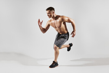 Wall Mural - Handsome muscular man with perfect torso running against white background