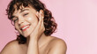 Leinwandbild Motiv Beautiful curly girl smiles as she likes skincare effect after beauty gel. Portrait of young woman washing her face and body, pink background