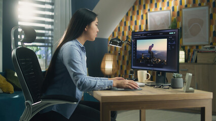 Wall Mural - asian woman editing photo in photoshop for customer on personal computer while sitting at the table 