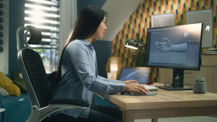 Wall Mural - asian woman sitting on chair at the table at home office and making 3d prototype of human hand in pr