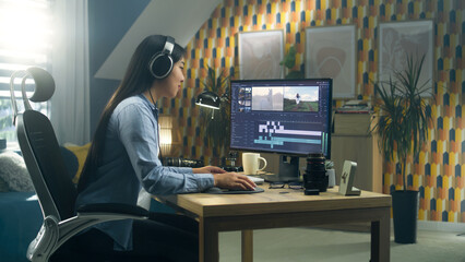 Wall Mural - asian woman sitting at the desk in headphones at home office and editing video for blog in professio