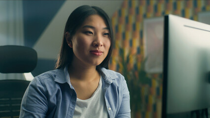 Wall Mural - asian woman sitting at the table at home office and working remotely on personal computer or browsin