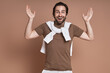 © gstockstudio - Excited young man gesturing and smiling while standing against brown background