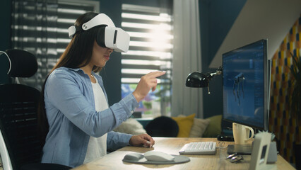 Wall Mural - asian woman sitting at the table at home office and using vr headset to work on 3d modeling project 