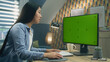 © Framestock - Asian woman sitting at the table and looking at screen of personal computer while working remotely from home or surfing the internet. Freelance. Green screen and chromakey