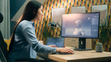 Wall Mural - asian woman creating 3d model of video game character in professional program using computer and dig