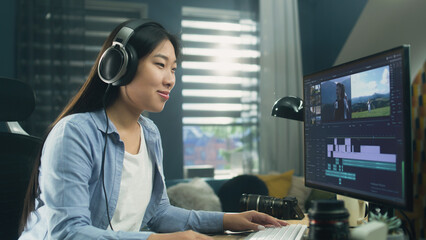 Wall Mural - female asian freelancer editing video for customer or travel blogger in program on computer while si