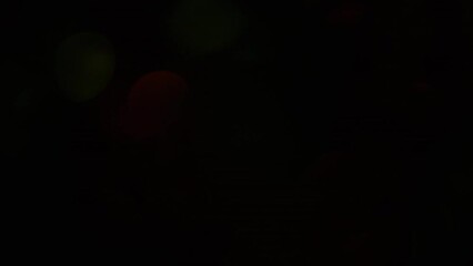 Wall Mural - Beautiful iridescence of reds and greens from Christmas bokeh on a dark background. A smooth movement of glowing shiny defocused circles. Can be used as Christmas or holiday background or overlay