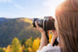 © Vladimir Razgulyaev - A woman photographer takes pictures of nature with a camera close-up view from the back free space. Autumn travel and active lifestyle.