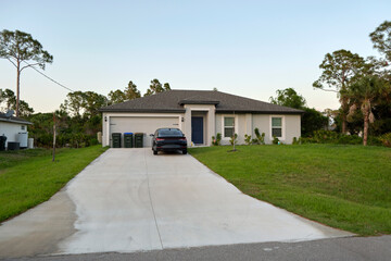 Wall Mural - Car parked in front of wide garage double door on concrete driveway of new modern american house