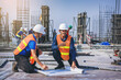 © Panumas - Structural engineer and foreman worker with blueprints discuss, plan working for the outdoors building construction site.