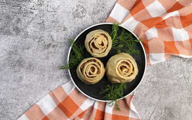 Wall Mural - Manti steamed Dumplings with meat and potatoes on a round plate on a dark gray background. Top view, flat lay