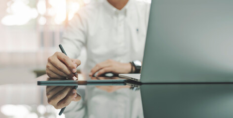 Wall Mural - young man writing business plan on digital tablet at desk in modern coworking office. copy space