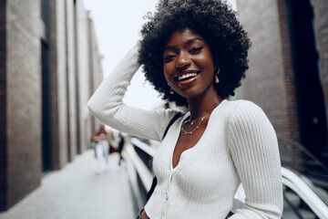 Wall Mural - Portrait of young african woman with hairstyle smiling in urban background