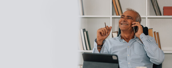 mature man in the office or at home talking on the phone