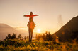 © Westend61 - Smiling woman carrying daughter with arms outstretched on shoulder at mountain