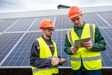 two young men in special helmets make notes after inspecting the solar panels.