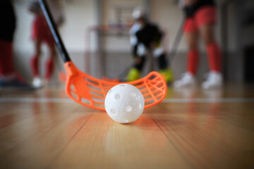 Sticker - Close-up of floorball stick and ball during woman floorball match in gym.